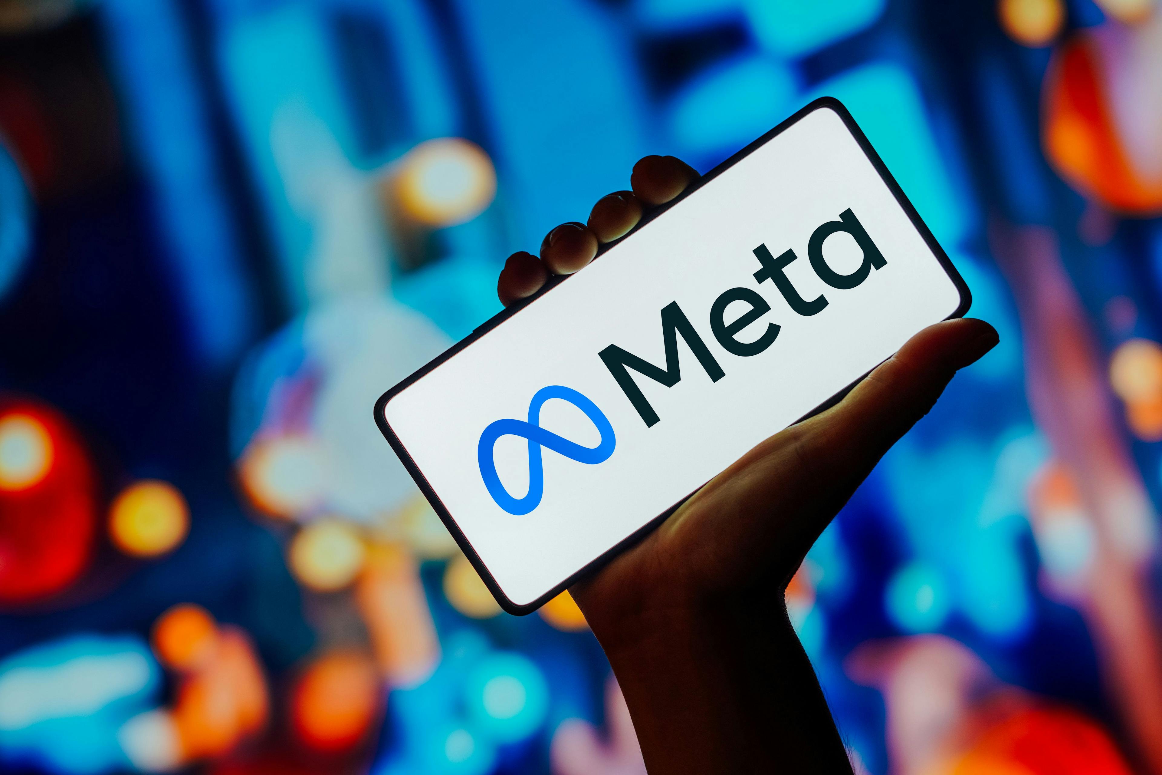 An arm holding a phone screen with a Meta logo